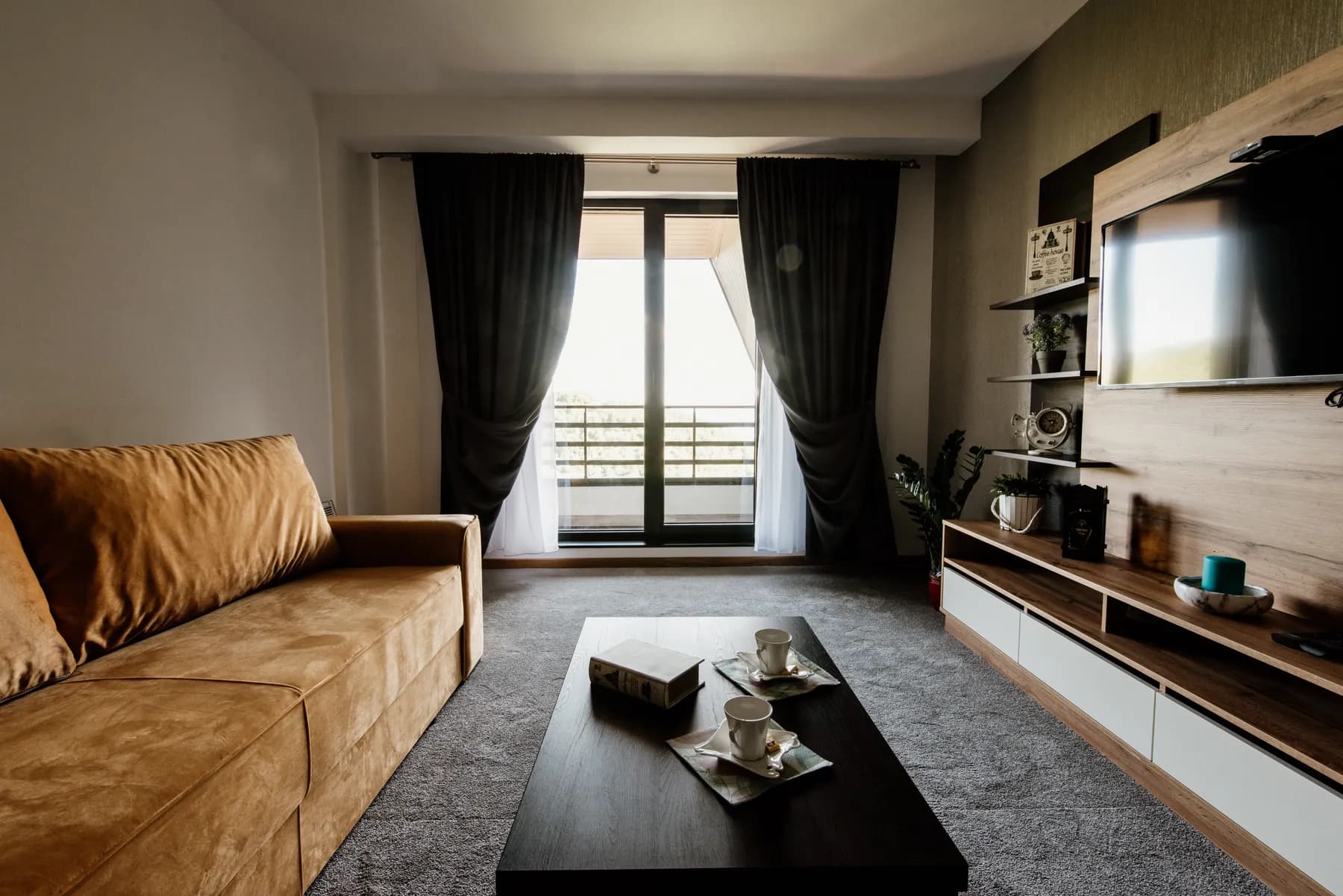 A tidy, modern living room with a sofa and large windows